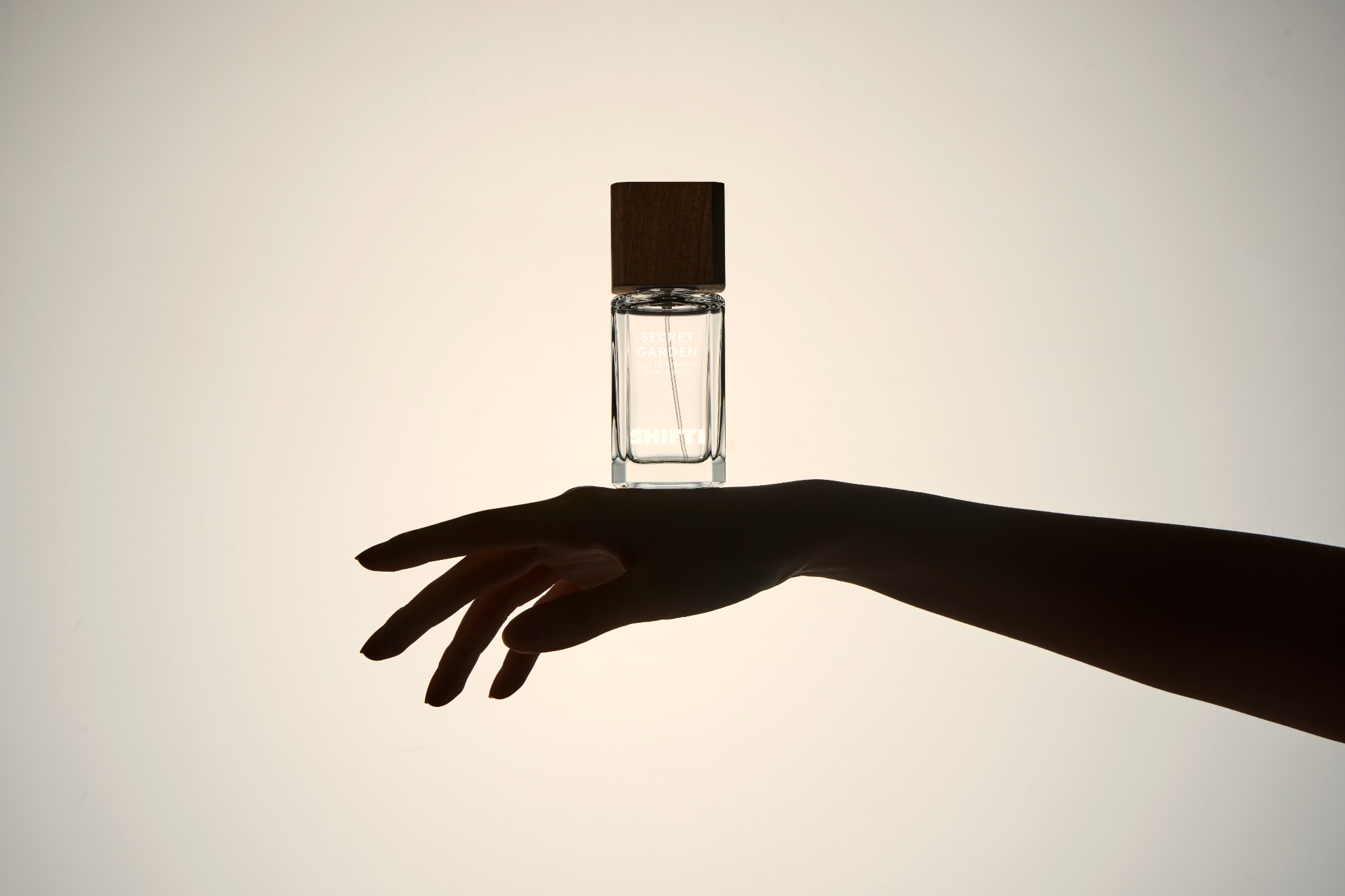 A refined silhouette shot of a SHIFTI perfume bottle balanced above an elegant hand.