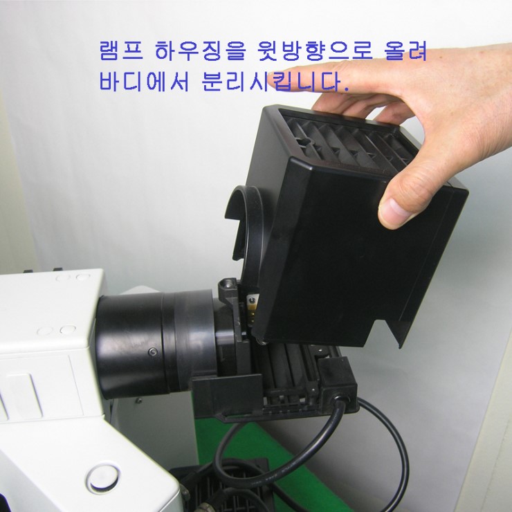 올림푸스 현미경 램프 하우징을 위로 들어 분리하는 모습
